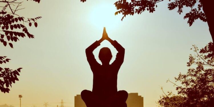 A silhouette of a person meditating outdoors at sunrise, symbolizing reflection and new beginnings.