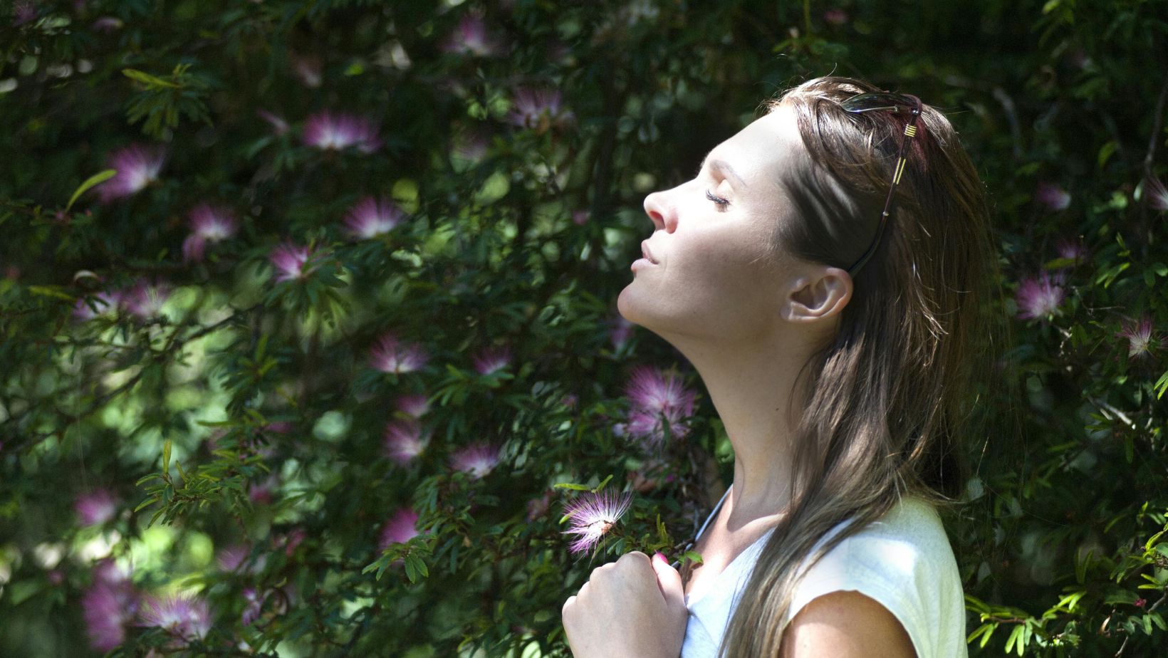A woman standing outside with eyes closed 

